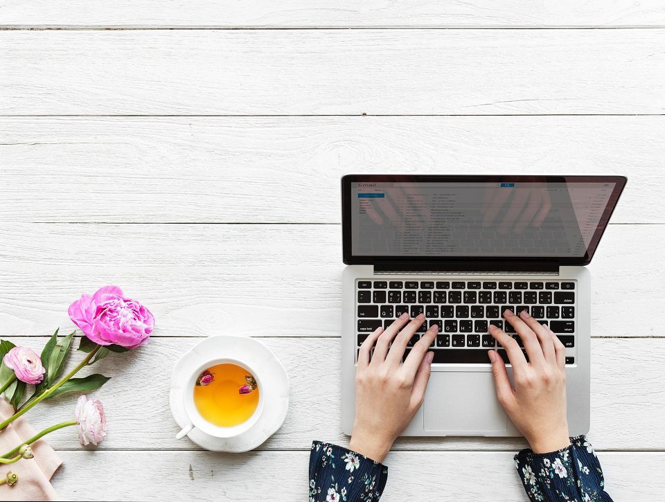 A laptop and cup of tea on a picnic table.