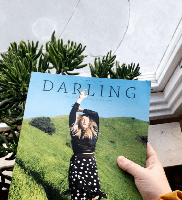 Darling Magazine being held near a window with plants